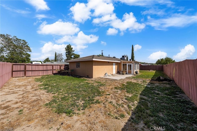rear view of house with a fenced backyard, stucco siding, a yard, and a patio area