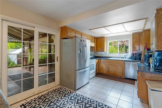 24851 Stem Ave, Lake Forest, CA 92630 - kitchen with appliances with stainless steel finishes, brown cabinets, light tile patterned flooring, under cabinet range hood, and dark countertops