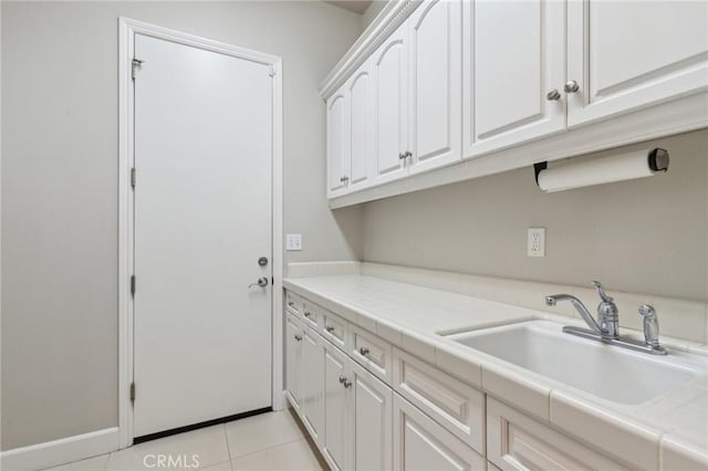 washroom featuring light tile patterned floors, baseboards, and a sink