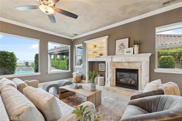 living area featuring visible vents, ornamental molding, ceiling fan, and a premium fireplace
