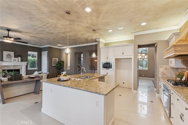 kitchen with a kitchen island with sink, light tile patterned floors, stainless steel appliances, a fireplace, and a sink