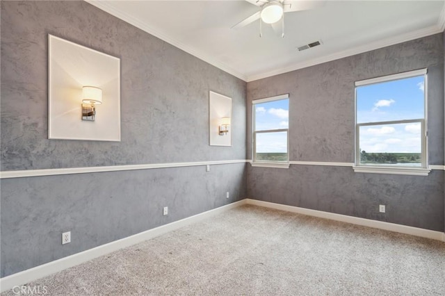 carpeted empty room with crown molding, a ceiling fan, visible vents, and baseboards