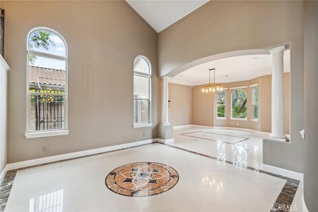 tiled empty room with ornate columns, high vaulted ceiling, arched walkways, and baseboards
