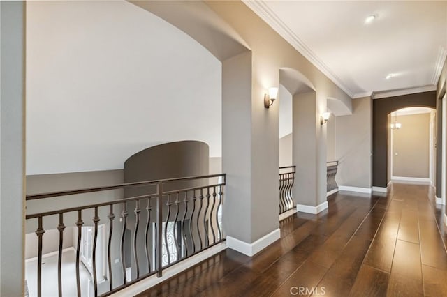 corridor with baseboards, arched walkways, hardwood / wood-style flooring, and crown molding