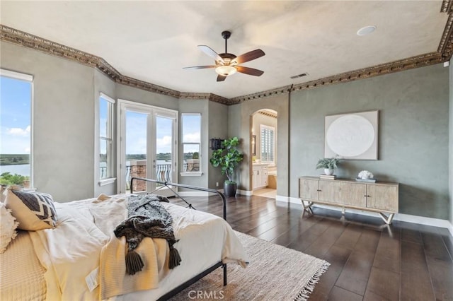 bedroom with visible vents, a water view, baseboards, arched walkways, and dark wood-style flooring