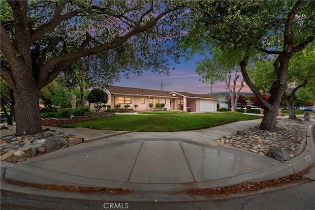 single story home featuring an attached garage, driveway, and a front yard