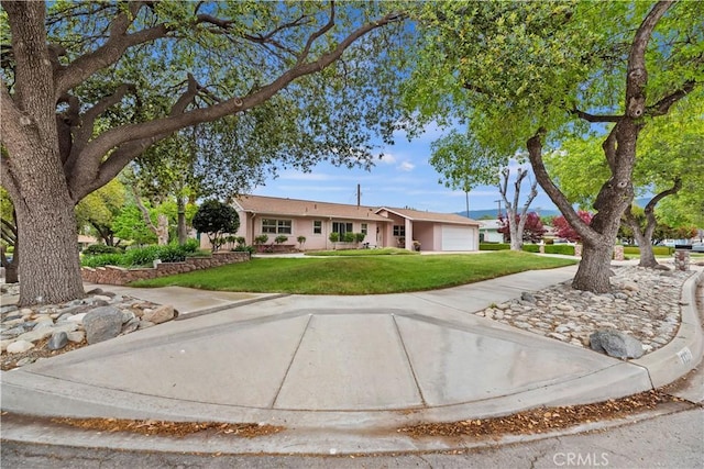 single story home featuring a garage, a front lawn, and concrete driveway