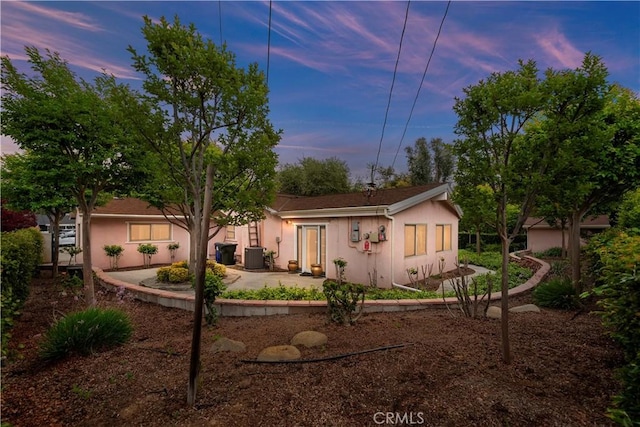 view of front of property featuring stucco siding, a patio area, and central AC