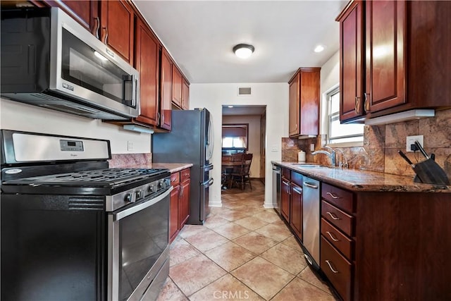 kitchen with visible vents, tasteful backsplash, a sink, dark stone countertops, and stainless steel appliances