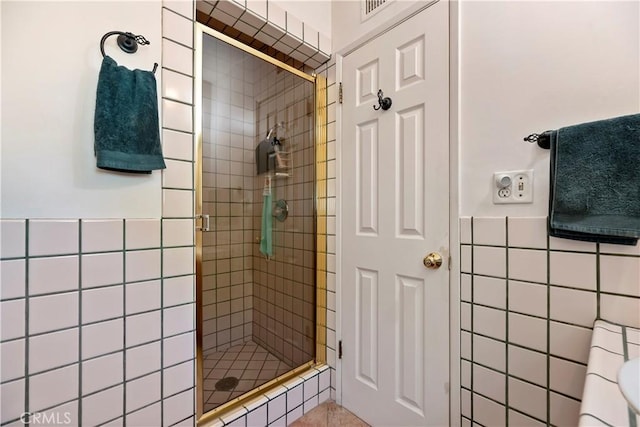 full bath with tile walls, a wainscoted wall, visible vents, and a stall shower
