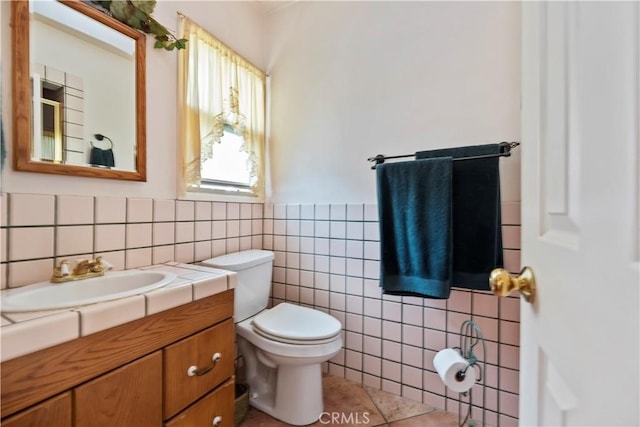 bathroom with toilet, tile walls, wainscoting, and vanity