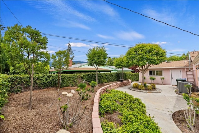 view of yard featuring central AC unit, a patio area, and fence
