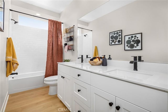 full bath featuring wood finished floors, toilet, double vanity, and a sink