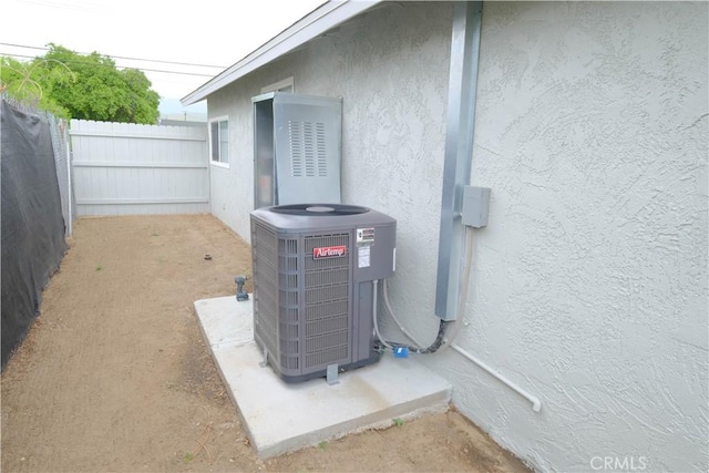 exterior details with fence, central AC, and stucco siding