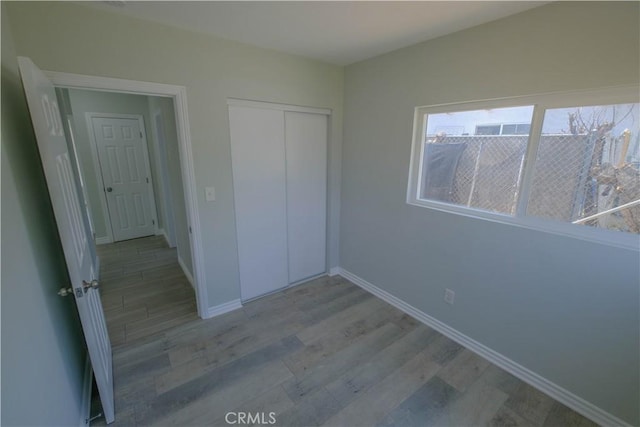 unfurnished bedroom with baseboards, a closet, and light wood-style flooring