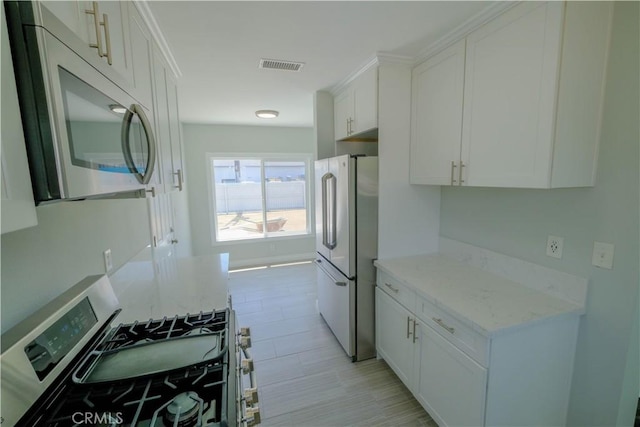 kitchen featuring white cabinetry, visible vents, appliances with stainless steel finishes, and light stone counters