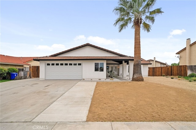 single story home featuring concrete driveway, a tile roof, stucco siding, fence, and a garage