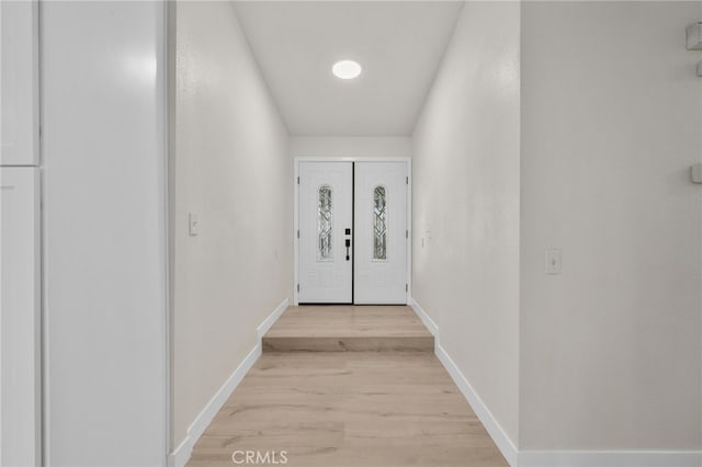 doorway with light wood-style flooring and baseboards