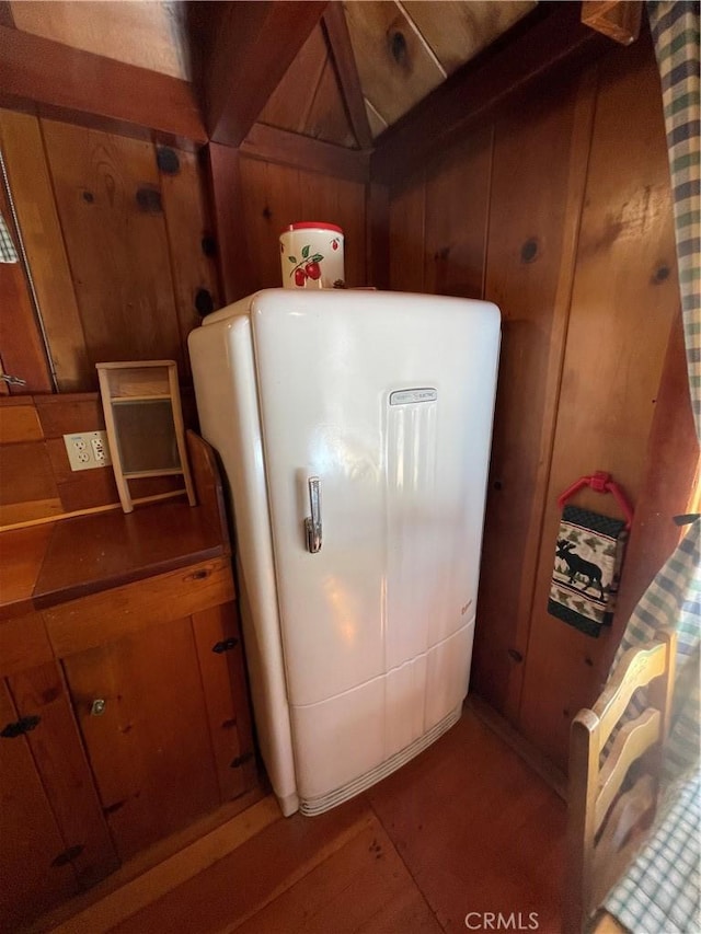 details with wooden walls and refrigerator