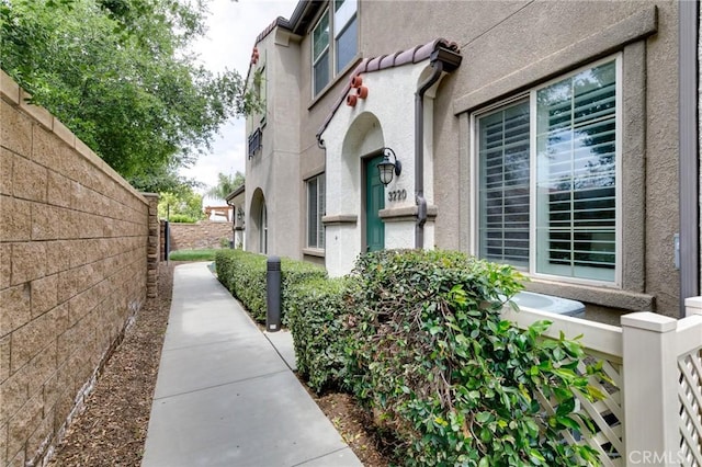 view of home's exterior with stucco siding and fence