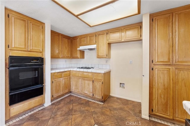15631 Via Cartagena St, Hesperia, CA 92345 - kitchen with under cabinet range hood, white gas stovetop, a warming drawer, tile countertops, and black oven