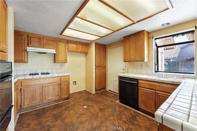 15631 Via Cartagena St, Hesperia, CA 92345 - kitchen with dark tile patterned floors, under cabinet range hood, black appliances, baseboards, and tile countertops