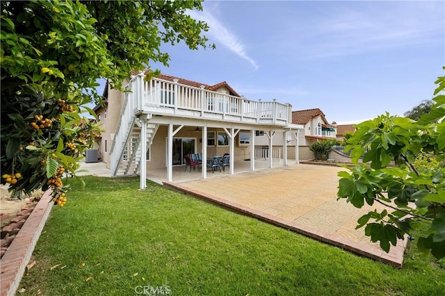 back of property with a wooden deck, a patio, stucco siding, a yard, and stairway