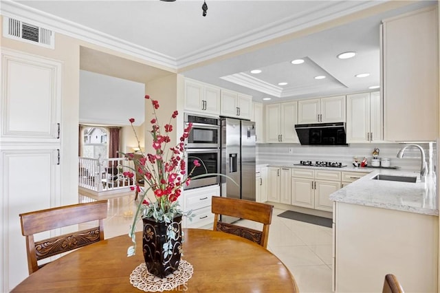kitchen with crown molding, a sink, stainless steel appliances, tasteful backsplash, and visible vents