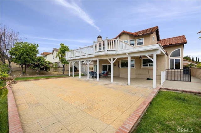 rear view of property featuring a deck, a patio area, stairway, fence, and stucco siding