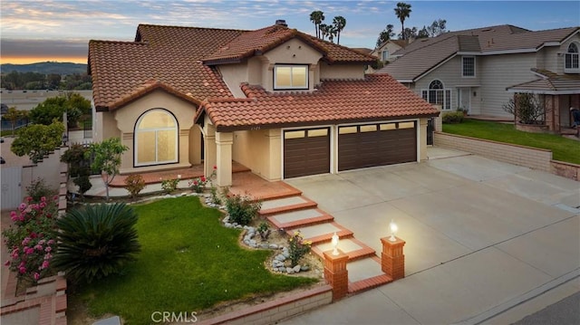 mediterranean / spanish house featuring concrete driveway, a front lawn, a tile roof, and stucco siding