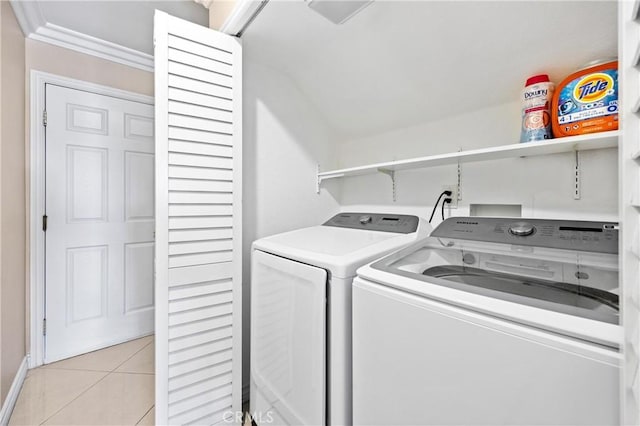 washroom featuring laundry area, crown molding, washing machine and dryer, light tile patterned floors, and baseboards
