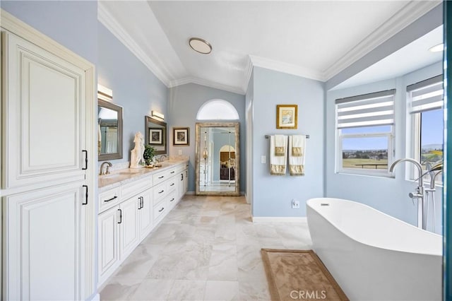 bathroom featuring crown molding, double vanity, a freestanding tub, baseboards, and vaulted ceiling