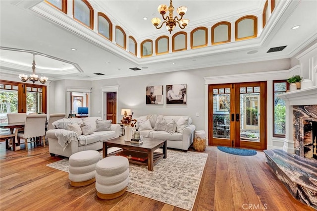 living room with an inviting chandelier, ornamental molding, light wood-style floors, and a fireplace
