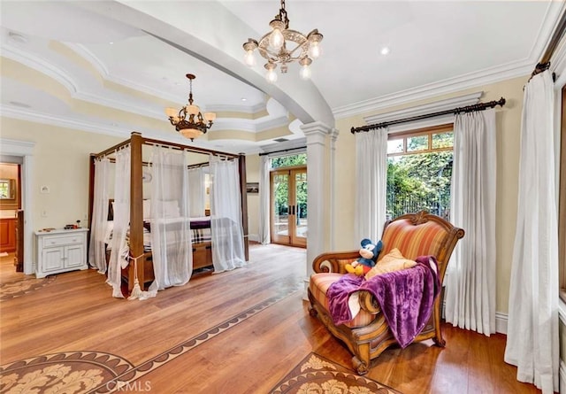 sitting room with ornamental molding, decorative columns, light wood-style floors, french doors, and a notable chandelier