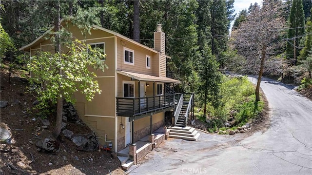 26131 Lake Forest Dr, Twin Peaks, CA 92391 - view of front facade with a chimney, stairs, and a deck