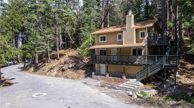 26131 Lake Forest Dr, Twin Peaks, CA 92391 - rear view of house with stairs, a chimney, stone siding, roof with shingles, and a deck