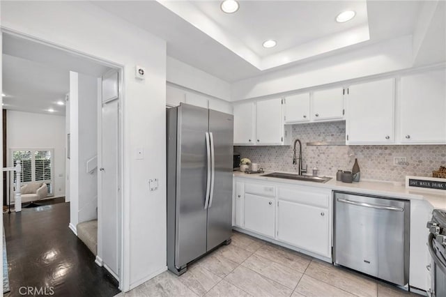 kitchen featuring tasteful backsplash, a sink, light countertops, white cabinets, and stainless steel appliances
