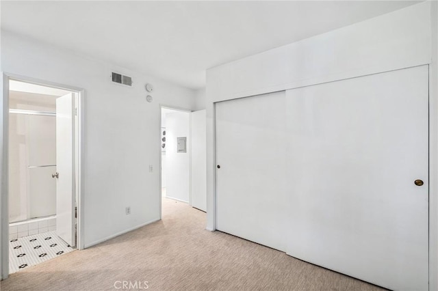 unfurnished bedroom featuring light carpet, a closet, connected bathroom, and visible vents