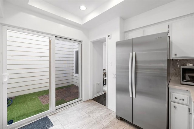 kitchen with light countertops, white cabinetry, appliances with stainless steel finishes, and a raised ceiling
