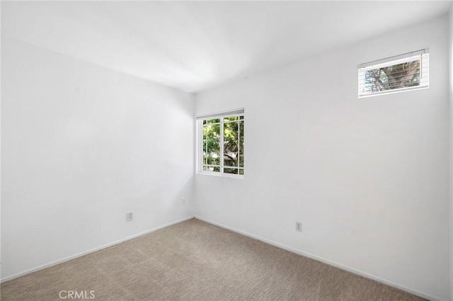 empty room featuring baseboards and light colored carpet