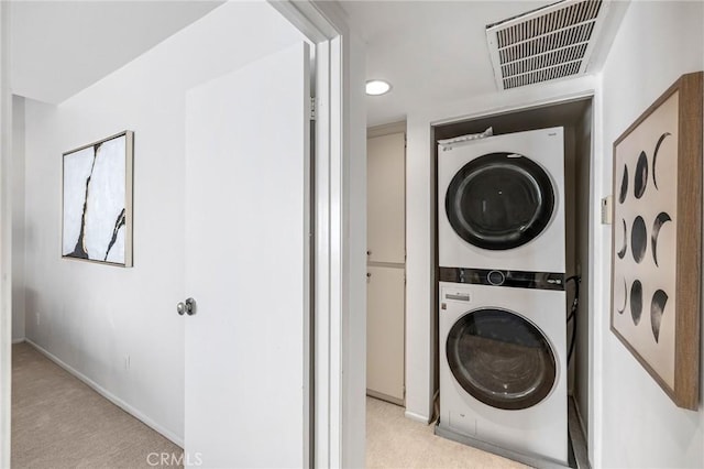 washroom with laundry area, visible vents, light carpet, baseboards, and stacked washer / drying machine