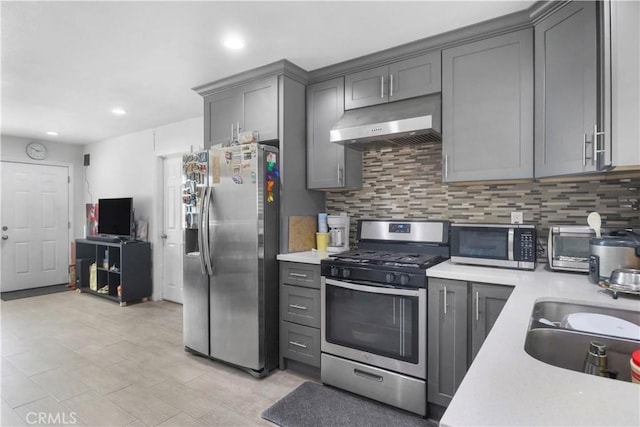 kitchen featuring gray cabinets, appliances with stainless steel finishes, under cabinet range hood, and light countertops