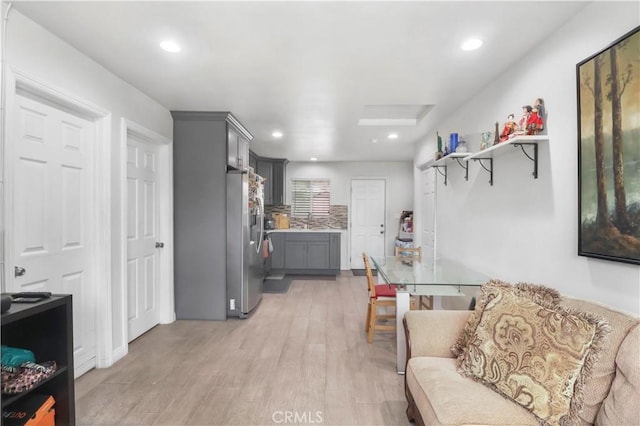 kitchen featuring a sink, light wood-style floors, gray cabinets, stainless steel refrigerator with ice dispenser, and light countertops