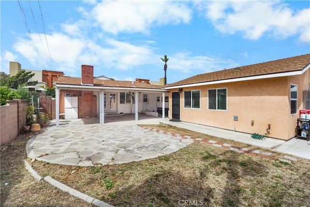 back of property featuring fence, a chimney, a patio area, and stucco siding