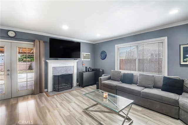 living area with recessed lighting, light wood-style floors, crown molding, a high end fireplace, and french doors