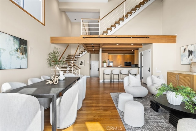 dining area with a towering ceiling, wood finished floors, and stairway