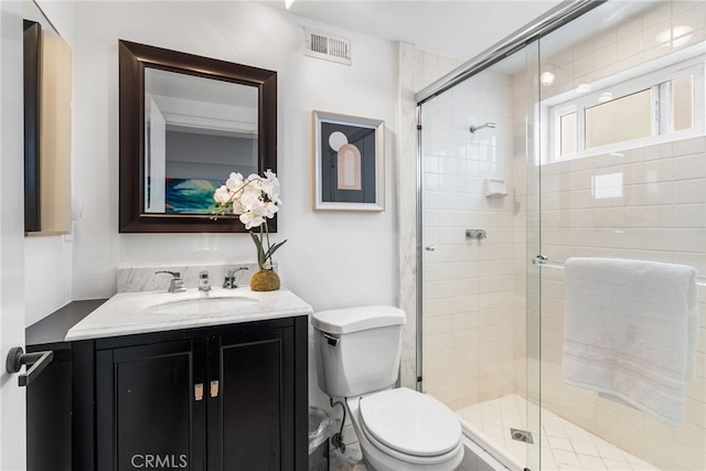 full bathroom featuring toilet, visible vents, a shower stall, and vanity