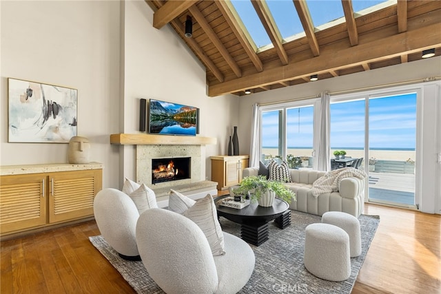 living room with a high end fireplace, high vaulted ceiling, beam ceiling, and wood finished floors