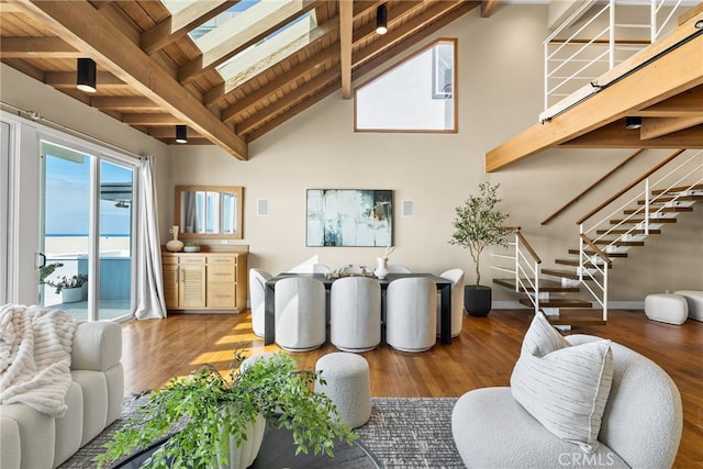 living area featuring beam ceiling, high vaulted ceiling, wood finished floors, and stairs