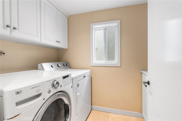 clothes washing area with light tile patterned floors, independent washer and dryer, cabinet space, and baseboards